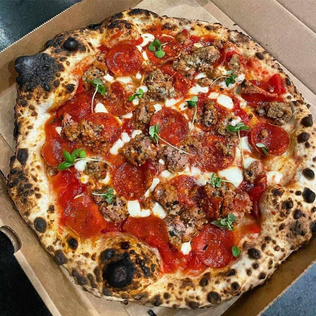 Stonebaked pizza topped with sausage, pepperoni and pancetta